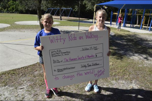 two girls hold up giant check showing money raised